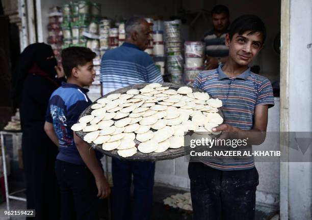 Syrian youth carries a tray of "Qatayef", traditional pancakes that are popular during the Muslim fasting month of Ramadan, in the northern town of...