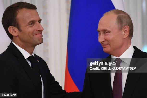 Russian President Vladimir Putin shakes hands with his French counterpart Emmanuel Macron at the end of a joint press conference following their...
