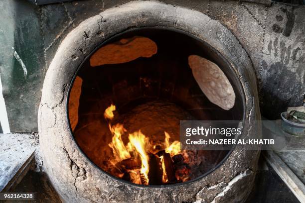Picture taken on May 24, 2018 shows traditional Syrian bread being baked in a kiln in the northern town of al-Bab.