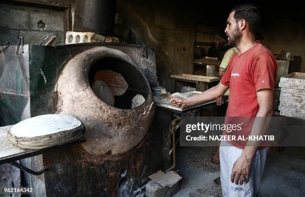 Syrian man prepares traditional bread in a kiln at a bakery in the northern town of al-Bab on May 24 to be consumed during the Iftar fast-breaking...