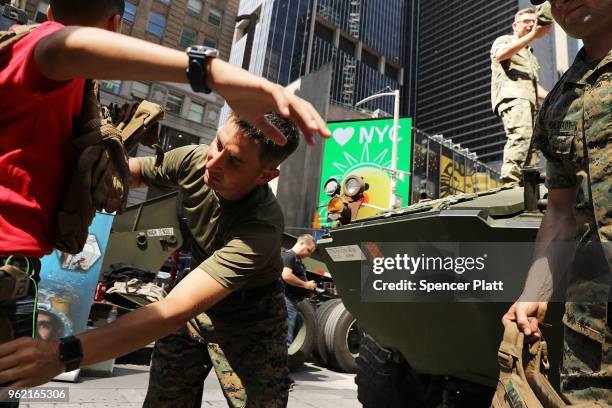 United States Marine places a ballistic jacket on a teenager during demonstrations and tours in Times Square as part of Fleet Week festivities May...