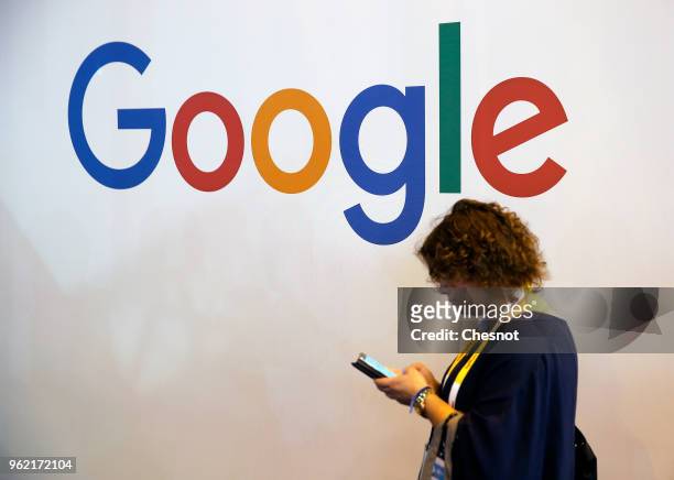 Visitor walks past in front of a Google logo during the Viva Technologie show at Parc des Expositions Porte de Versailles on May 24, 2018 in Paris,...