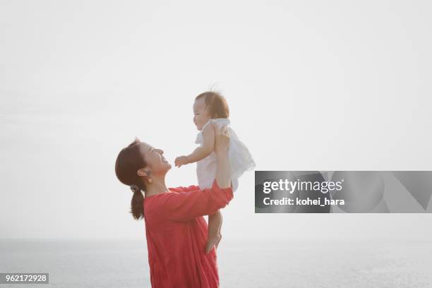 mutter und baby mädchen entspannt am meer - japanese mom stock-fotos und bilder