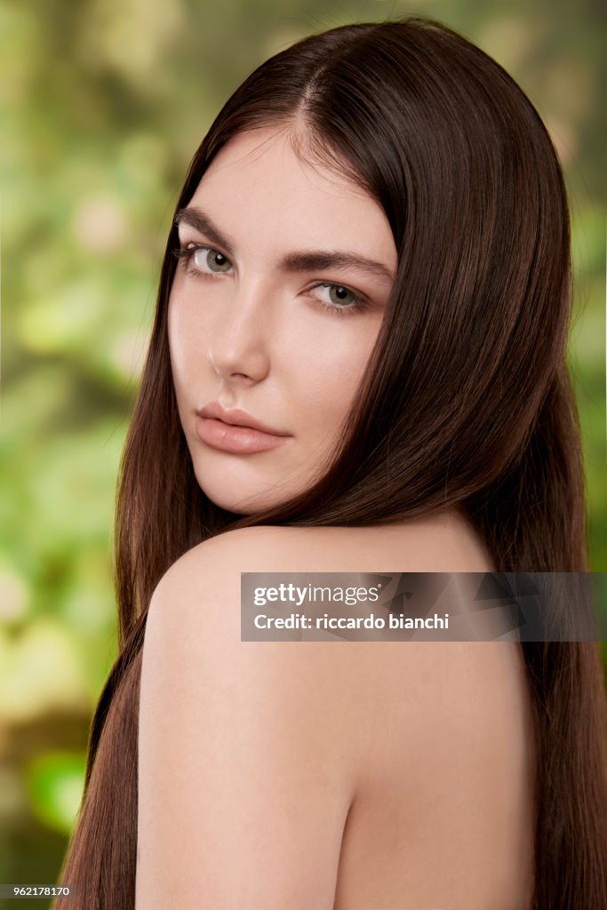 BRUNETTE WOMAN WITH NATURAL LOOK AND STRAIGHT HAIR ON NATURE BACKGROU