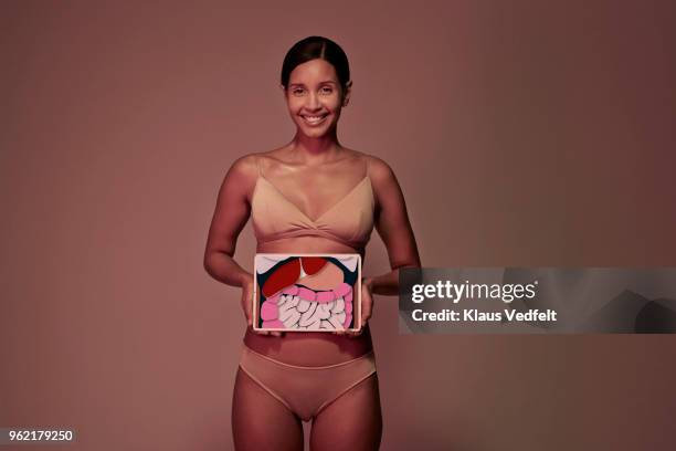 young woman holding tablet in front of stomach to look inside the body - abdomen xray stock pictures, royalty-free photos & images