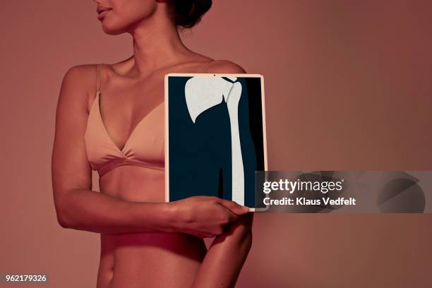 young woman holding tablet in front of body to show arm bone - escapula fotografías e imágenes de stock