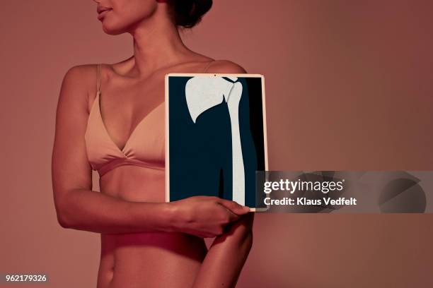 young woman holding tablet in front of body to show arm bone - scapula stock pictures, royalty-free photos & images