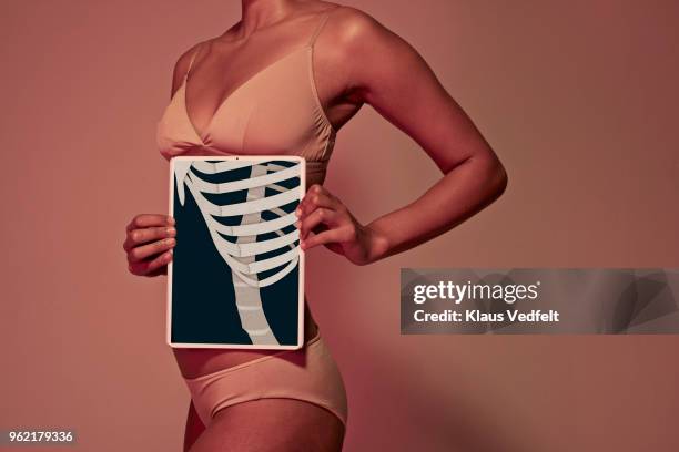 young woman holding tablet in front of body to show rib bones - rib cage bildbanksfoton och bilder