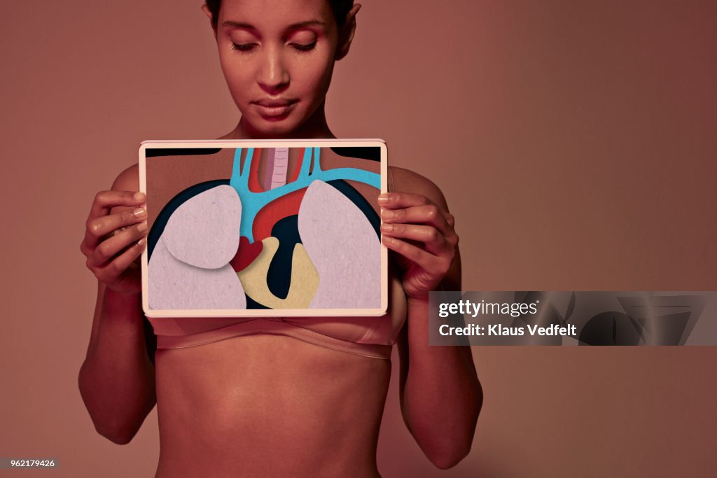 Young woman holding tablet in front of throat to show oesophagus