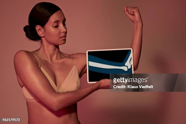 young woman holding tablet in front of body to show arm bone - opperarmbeen stockfoto's en -beelden
