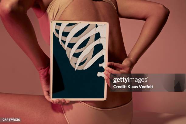 young woman holding tablet in front of back, to show backbone & ribs - halbbekleidet stock-fotos und bilder