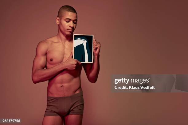 young man holding tablet in front of body to show shoulder & arm bone - escapula fotografías e imágenes de stock