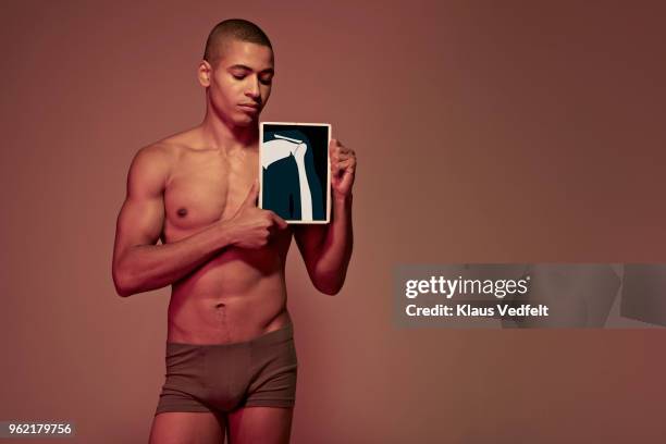 young man holding tablet in front of body to show shoulder & arm bone - opperarmbeen stockfoto's en -beelden