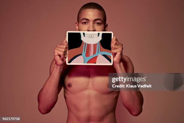 young man holding tablet in front of body to show jaw bone, oesophagus & top of lungs - human jaw bone stock-fotos und bilder