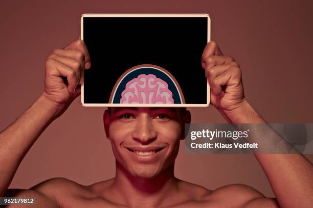 young man holding tablet in front of head to show brain - frontal lobe stock pictures, royalty-free photos & images