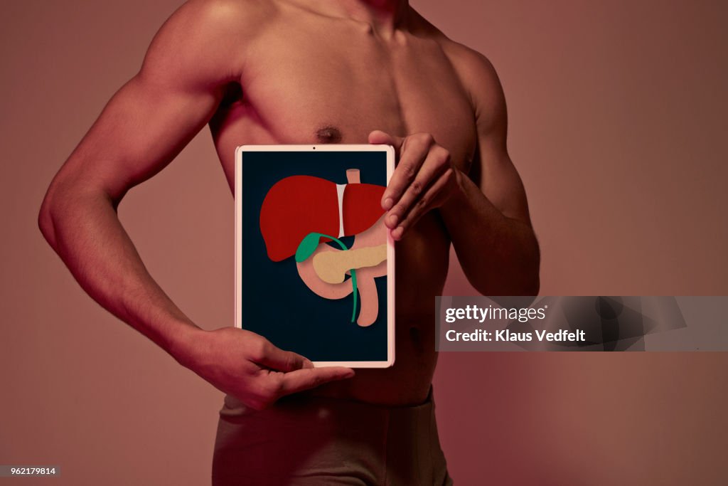 Young man holding tablet in front of body to display liver