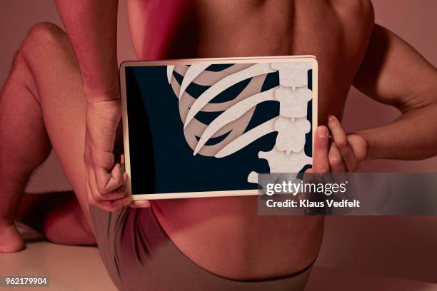 young man holding tablet in front of back to show ribs & back bone - low section stockfoto's en -beelden