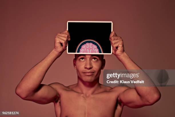 young man holding tablet in front of head to show brain - scientific imaging technique stock pictures, royalty-free photos & images