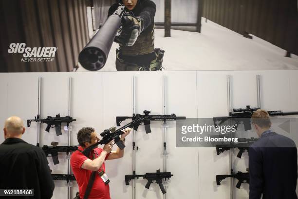 An attendee holds up a SIG Sauer Inc. Rifle during the Special Operations Forces Industry Conference in Tampa, Florida, U.S., on Tuesday, May 22,...