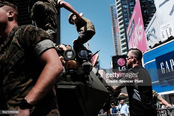 United States Marine helps a child climb on a military vehicle during demonstrations and tours in Times Square as part of Fleet Week festivities May...