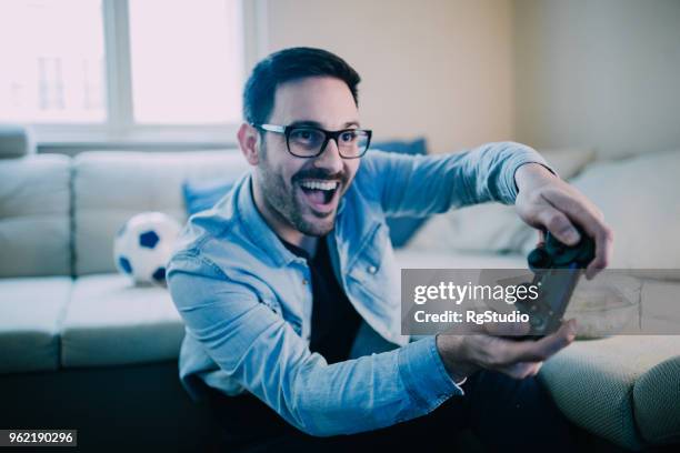 excited man playing video games - gaming championship stock pictures, royalty-free photos & images
