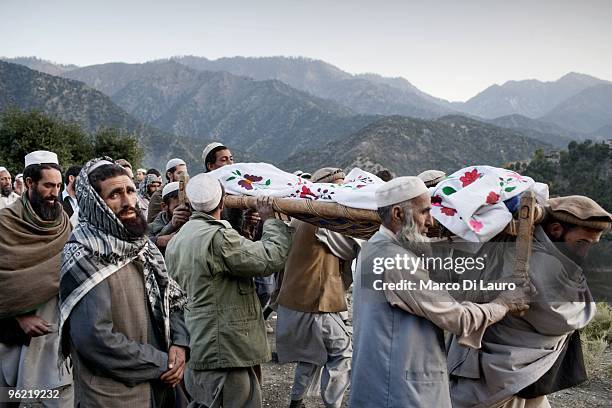 The body of one of two children killed during an explosion is carried on a makeshift stretcher by local residents during his funeral as US Army...