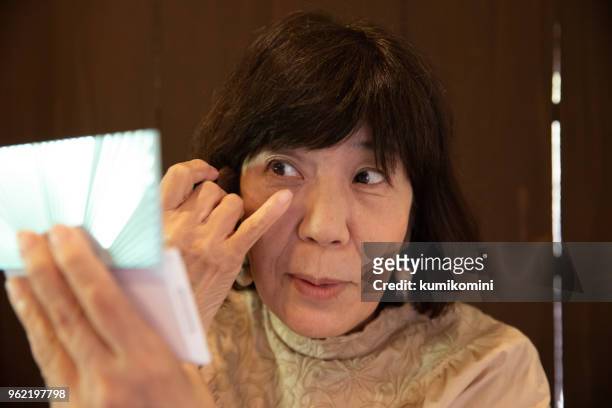年配の女性が化粧をかけること - eye make up ストックフォトと画像
