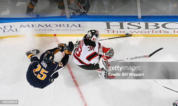 Michael Grier of the Buffalo Sabres reaches in for the puck against Martin Brodeur of the New Jersey Devils on January 27, 2010 at HSBC Arena in...
