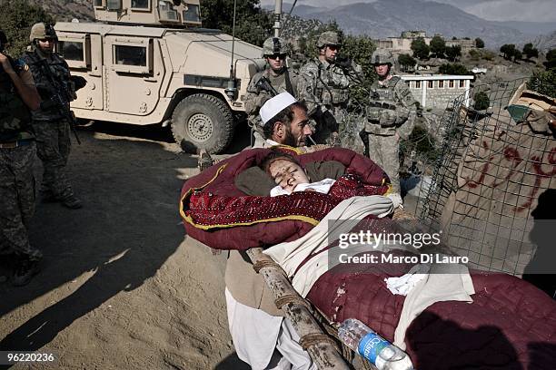 An Afghan villager bring into the Korengal Outpost a wounded children to be treated by US Army medics of B Company, 2nd Battalion,12th Infantry...