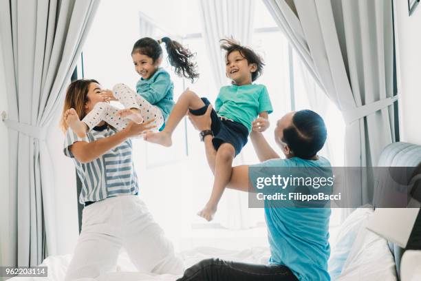 multi ethnic family playing together on the bed - a boy jumping on a bed stock pictures, royalty-free photos & images