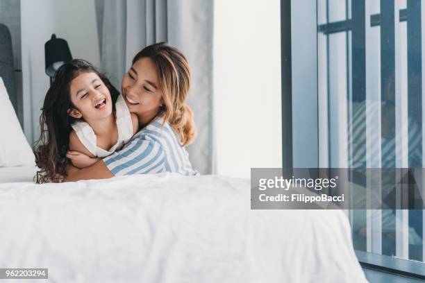 moeder en dochter spelen samen op het bed - chinese mothers day stockfoto's en -beelden