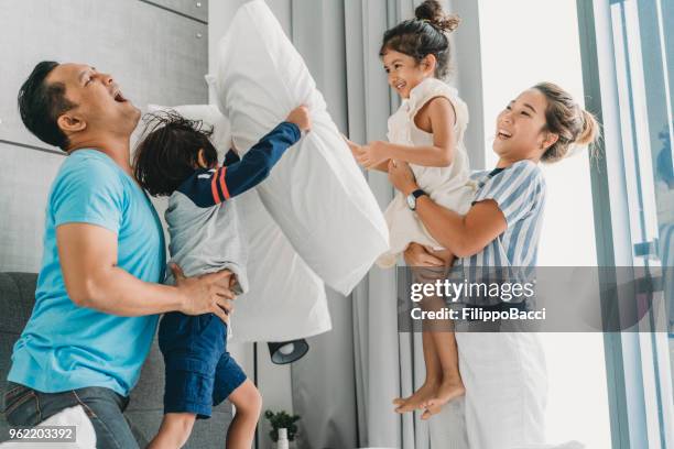 happy family on the bed together - father and child and pillow fight stock pictures, royalty-free photos & images