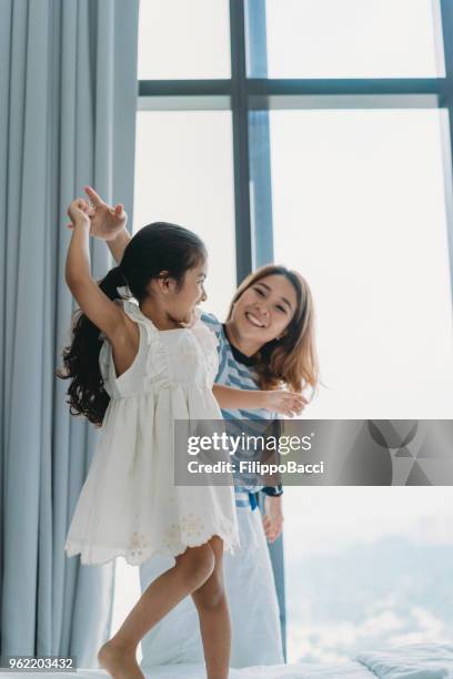 mother and daughter playing together on the bed - chinese dance stock pictures, royalty-free photos & images