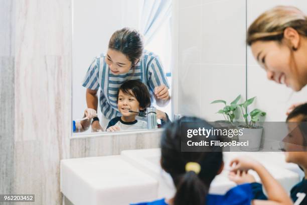 bruder und schwester zähneputzen mit mama - brothers bathroom stock-fotos und bilder