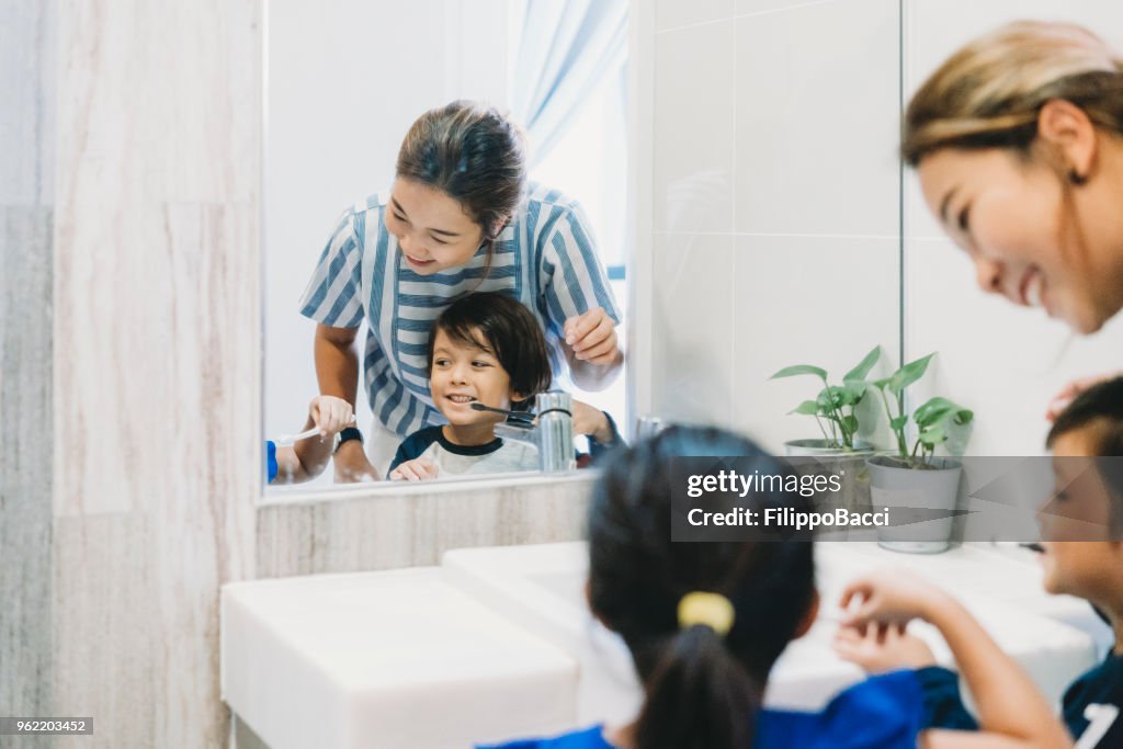 Brother and sister brushing their teeth with mom