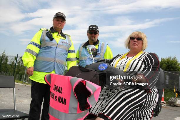 A disabled Anti-Frack Protester on a Mobility Scooter, watched by Two Police Liaison Officers attempts to block the gates of the Fracking company...
