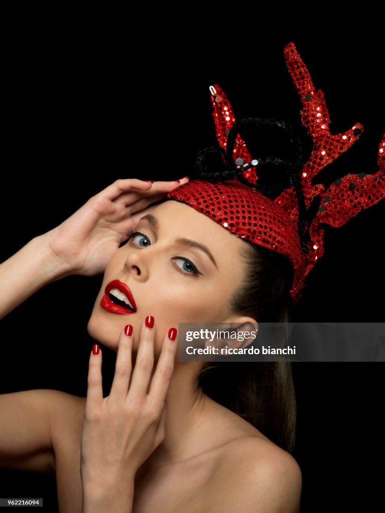 Portrait_of_brunette woman with red fashion paillettes crown red lipstick and red nail polish