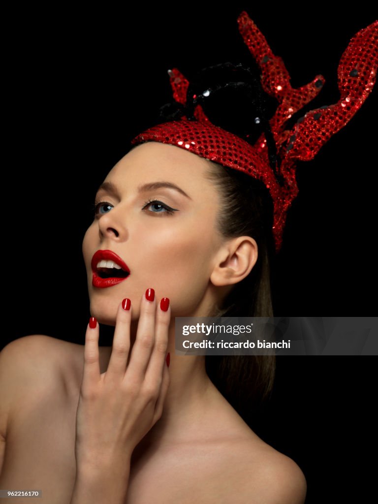 Portrait_of_brunette woman with red fashion paillettes crown red lipstick and red nail polish