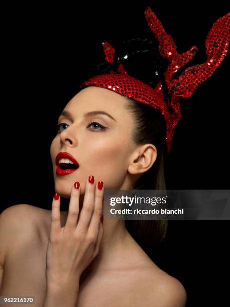 portrait_of_brunette woman with red fashion paillettes crown red lipstick and red nail polish - thin lips stock pictures, royalty-free photos & images