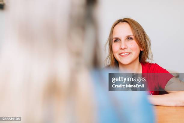 een jonge vrouw is glimlachend en luisteren op een maatschappelijk werker - maatschappelijk werker stockfoto's en -beelden