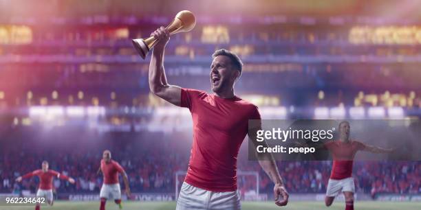 professional soccer player holding up gold trophy in victory celebration - holding trophy stock pictures, royalty-free photos & images