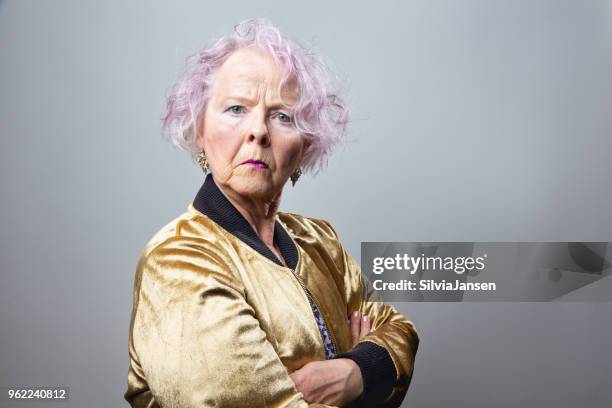 ältere frau mit rosa haaren und goldenen jacke - coole oma stock-fotos und bilder