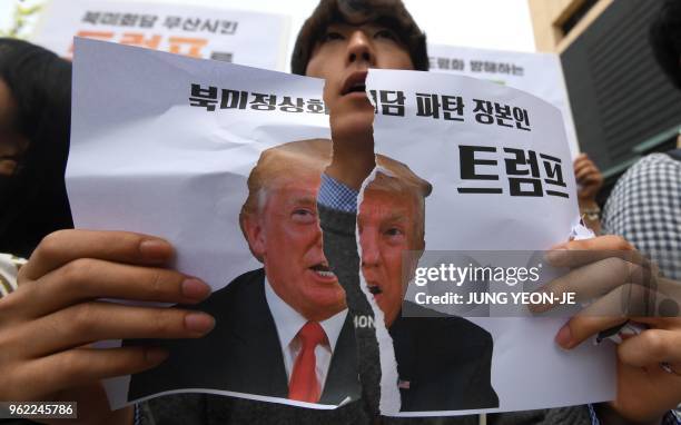 Protester tears a picture of US President Donald Trump during an anti-Trump rally near the US embassy in Seoul on May 25, 2018. - North Korea said on...