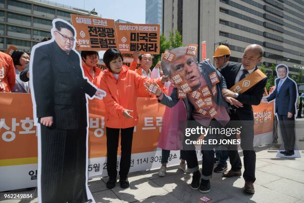 An anti-US protester wearing a face-mask depicting US president Donald Trump is led between cardboard cutouts of North Korean leader Kim Jong Un and...