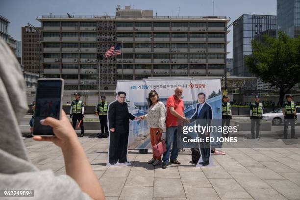 People pose for photos with a cardboard cutouts of North Korean leader Kim Jong Un and South Korean leader Moon Jae-in following a rally by an...