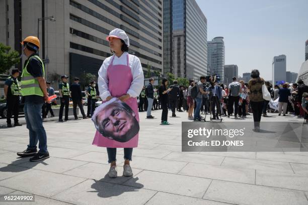 An anti-US protester holds a face-mask depicting US president Donald Trump during a rally calling for more dialogue between the three leaders,...