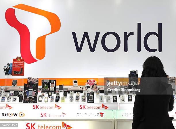 Customer looks at mobile phones displayed in front of an SK Telecom Co. Advertising board at an electronics shop in Seoul, South Korea, on Thursday,...