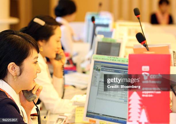 Employees speak on the phone at SK Telecom Co.'s T World brand shop in Seoul, South Korea, on Thursday, Jan. 28, 2010. SK Telecom Co., South Korea's...