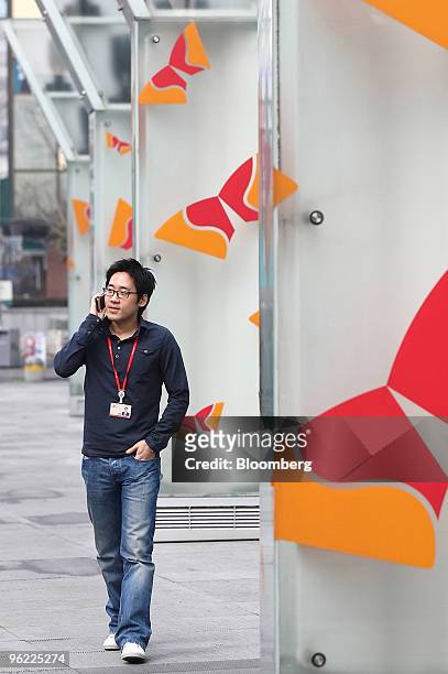 An employee of SK Telecom Co. Using a mobile phone walks past the company's headquarters in Seoul, South Korea, on Thursday, Jan. 28, 2010. SK...