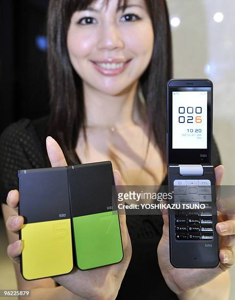Japan's mobile communication giant KDDI employee displays the new design conscious mobile phone "Lotta", meaning a lot of fun, produced by Japanese...